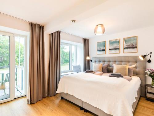 een slaapkamer met een groot bed en een groot raam bij FeWo Prora - Baltic Beach Home in Binz