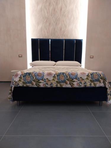 un letto con testiera nera e coperta di Suite al Borgo ad Aversa