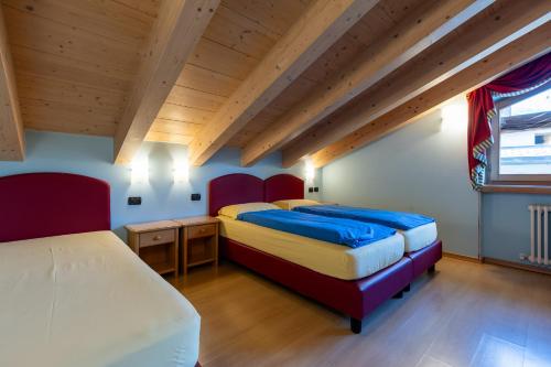 2 letti in una camera con soffitti in legno di Bait Da Menin a Livigno