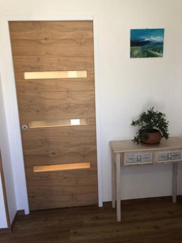 une porte dans une pièce avec une table et une plante dans l'établissement La Maison d'à Coté, à Saint-Georges-sur-Cher