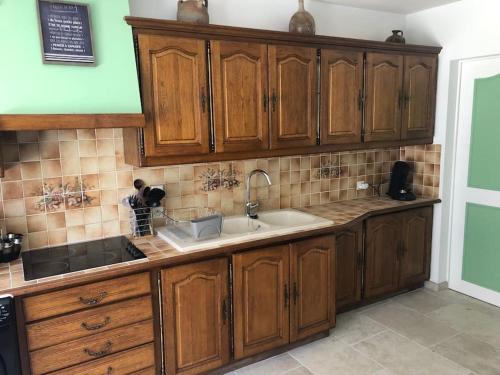 une cuisine avec des armoires en bois et un évier dans l'établissement La Maison d'à Coté, à Saint-Georges-sur-Cher