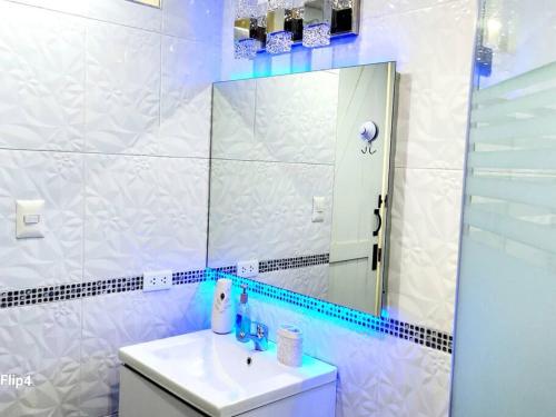 Baño blanco con lavabo y espejo en Mini Departamento Acogedor, en La Molina