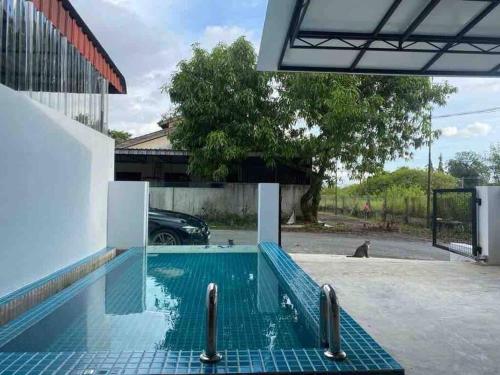 a swimming pool in a parking lot next to a building at Zen Retreat Glass Pool Villa in Kamunting