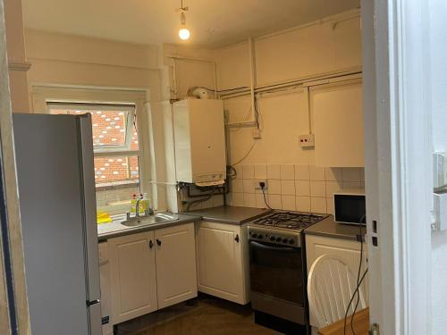 a kitchen with white cabinets and a stove top oven at Rahal Hotel Hackney London in London