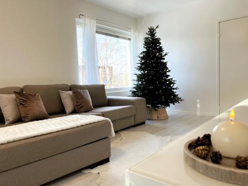 Una sala de estar con un sofá y un árbol de Navidad. en Arctic Luxury Apartment, en Rovaniemi