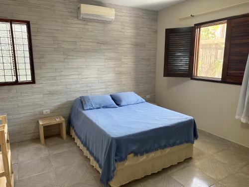 ein Schlafzimmer mit einem Bett mit blauer Bettwäsche und einer Ziegelwand in der Unterkunft Casa Praia de Gaibu in Cabo de Santo Agostinho