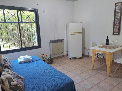 a room with a bed and a table and a refrigerator at Rincón Verde Chacras de Coria in Ciudad Lujan de Cuyo