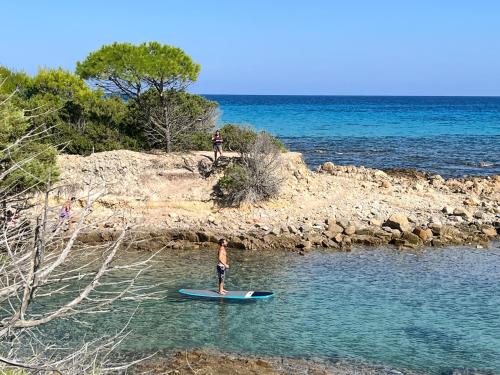 a man standing on a surfboard in the water at Casa Lia - Independent apartment in the Gulf of Orosei in Galtellì