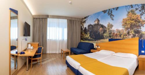 a hotel room with a king sized bed and a desk at Hotel Express Aosta East in Aosta