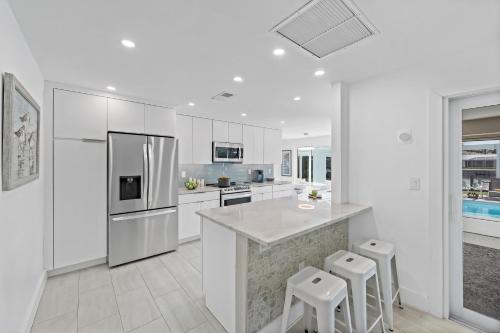 a white kitchen with a refrigerator and stools at Direct boating access home in Olde Marco with pool in Marco Island