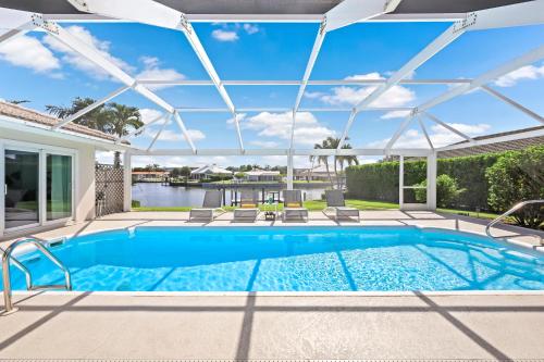 a swimming pool with a pergola and a house at Direct boating access home in Olde Marco with pool in Marco Island