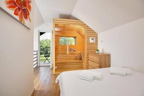 a bedroom with a white bed and a wooden wall at Kuca za odmor Villavera in Donja Lomnica