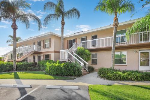 a building with palm trees in front of it at Quaint Naples condo with pool and short drive to Marco in Naples