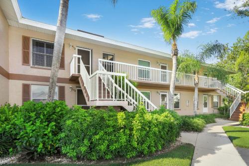 a apartment building with stairs and palm trees at Quaint Naples condo with pool and short drive to Marco in Naples