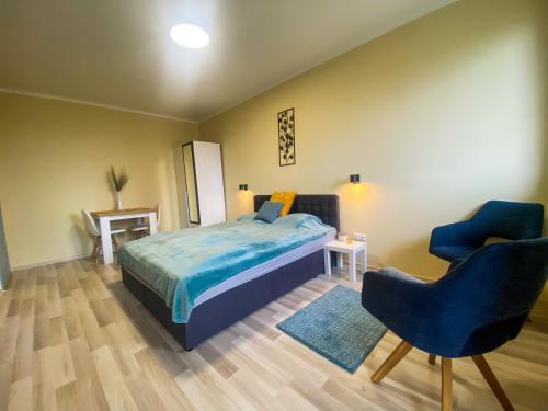 ein Schlafzimmer mit einem Bett und zwei blauen Stühlen in der Unterkunft Fresh smartly designed Studio Flat & sunny balcony in Budapest