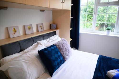 a bedroom with a bed with white sheets and a window at Charming 2-bedroom House near Bourton Park in Buckingham in Buckingham