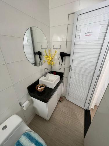 a bathroom with a sink and a toilet and a mirror at POUSADA CASA DA CLAUDIA MARAGOGI in Maragogi