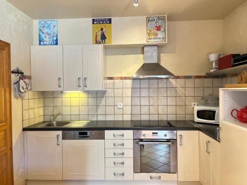 une cuisine avec des armoires blanches et un four à plaques de cuisson dans l'établissement Appartement avec Terrasse au Pied des Pistes, Centre des Gets, 3 Étoiles, 6 pers., Animaux Acceptés - FR-1-623-280, aux Gets