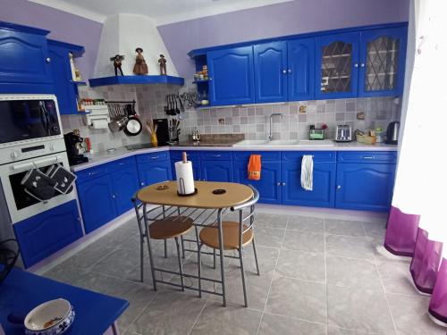 a blue kitchen with a table and blue cabinets at HAUT VILLA MESANGES EN BORD DE MER ! in Lucciana