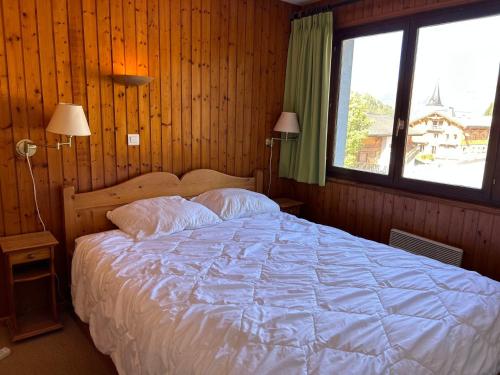 une chambre avec un grand lit avec une grande fenêtre dans l'établissement Appartement spacieux aux Gets, pied des pistes, balcon sud-ouest, 2 chambres, coin cabine, garage, WiFi - FR-1-623-81, aux Gets