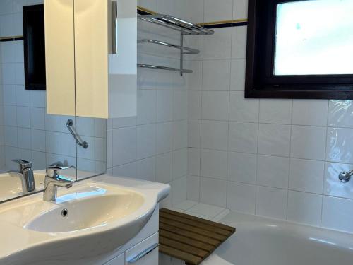La salle de bains blanche est pourvue d'un lavabo et d'une baignoire. dans l'établissement Appartement spacieux aux Gets, pied des pistes, balcon sud-ouest, 2 chambres, coin cabine, garage, WiFi - FR-1-623-81, aux Gets
