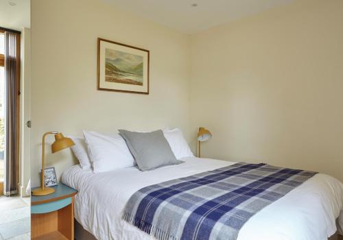 1 dormitorio con 1 cama con manta azul y blanca en The Old Barn at Moor Farm, en Godshill