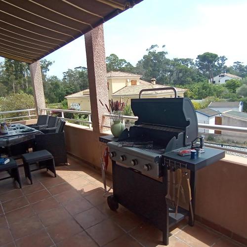 a grill on a patio with a table and chairs at HAUT VILLA MESANGES EN BORD DE MER ! in Lucciana