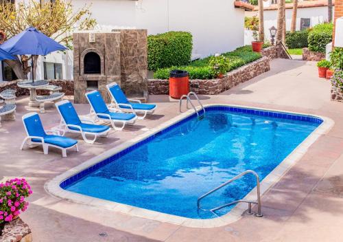 uma piscina com cadeiras, uma mesa e um guarda-sol em WIVC La Paloma Resort - Your Vacation Escape to Rosarito, Swimming Pool & Short Walk To The Beach em Popotla