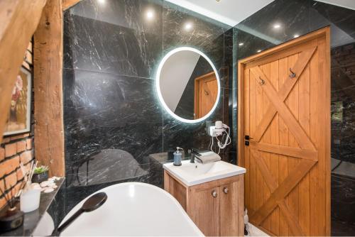 W łazience znajdują się drewniane drzwi, umywalka i lustro. w obiekcie Przytulny Apartament Z Wieżą w mieście Gliwice