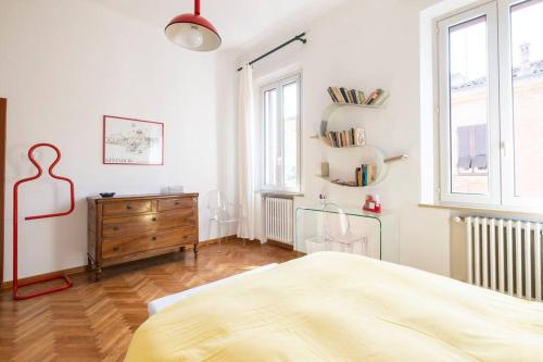 a bedroom with a bed and a dresser and windows at Vicolo Parchetto 9 in Ferrara