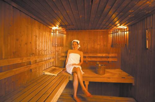 a woman sitting on a bench in a sauna at Kantary House Hotel, Bangkok in Bangkok