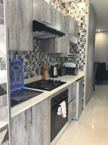 a kitchen with a stove and a laptop on the counter at Innisfree Apartments in Gaborone