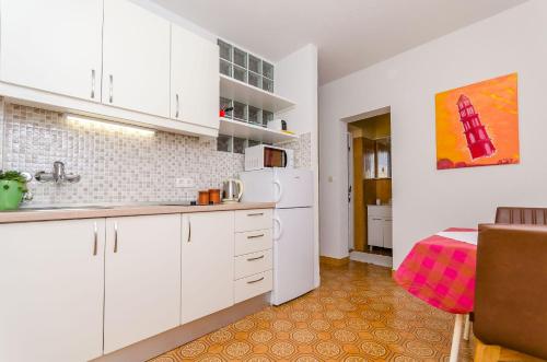a kitchen with white cabinets and a table in a room at Apartments and Rooms Darinka in Vrboska