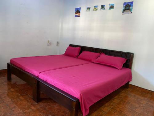 a large bed with a pink blanket on it at Beach Guest House Addalaichenai in Addalachenai