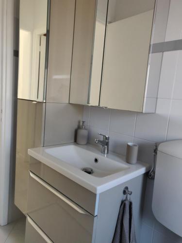 a bathroom with a white sink and white cabinets at Appartement Vue Mer Menton in Menton