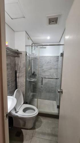 a bathroom with a shower and a toilet and a sink at Affordable Condo in Makati w/ Wi-Fi, Netflix, Pool in Manila