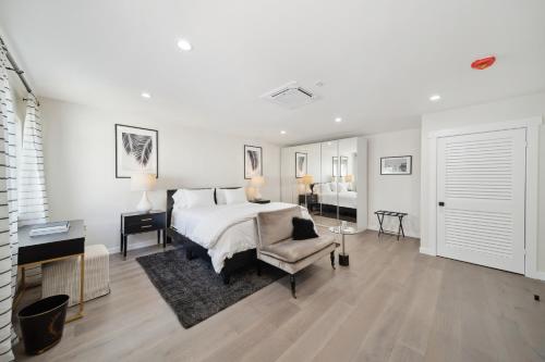 um quarto branco com uma cama, uma cadeira e uma secretária em Chic Executive - Historic Floral Park Guest House bungalow em Santa Ana