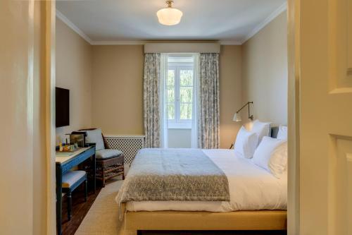 a bedroom with a bed and a desk and a window at Valverde Santar Hotel & SPA - Relais & Châteaux in Santar