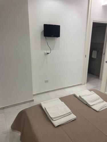 two towels on a bed with a tv on the wall at San Donato Apartment in Barletta