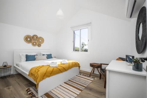 1 dormitorio blanco con 1 cama con manta amarilla en Blue House - By Wehost, en Ponta do Sol