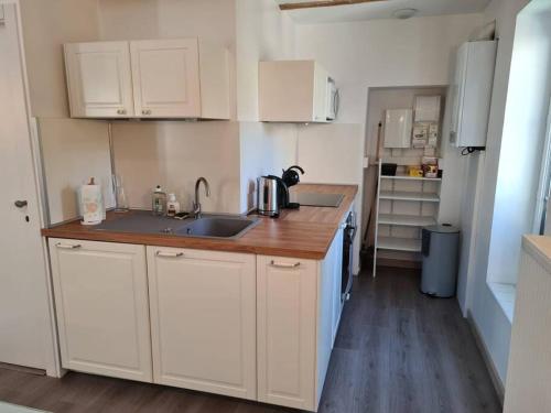 una piccola cucina con armadi bianchi e lavandino di Joli appartement tout confort a Chalon-sur-Saône