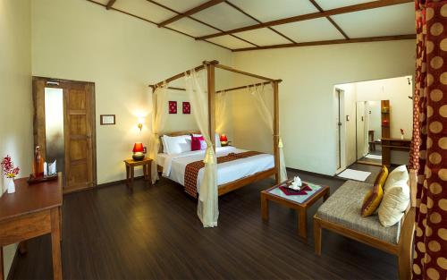 a bedroom with a canopy bed and a living room at Neelakurunji Plantation Munnar in Chinnakanal