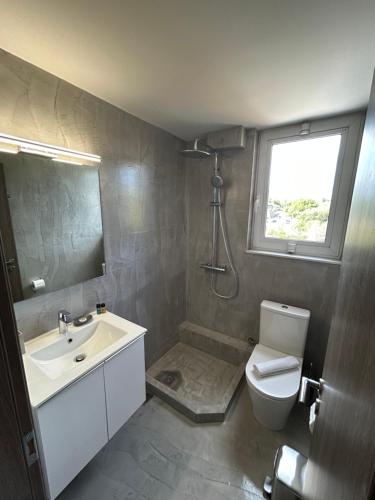 a bathroom with a sink and a toilet and a window at Peania Domus in Paianía