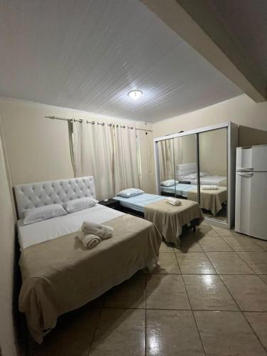 a hotel room with two beds and a refrigerator at Suítes em Cabo Frio in Cabo Frio