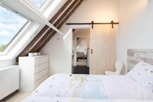 1 dormitorio con cama blanca y ventana en Iselmarpleats 3 kamer appartement, en Gaast