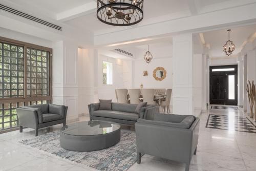 a living room with a couch and chairs and a table at Luxury Allegria Golf Villa with pool in Sheikh Zayed