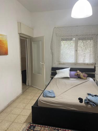 a bedroom with a large bed with a window and a door at Asaf place in Haifa