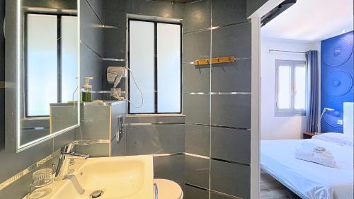 a bathroom with a sink and a mirror and a bed at Hotel Le Florian in Cannes