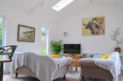 a living room with two couches and a tv at The Garden Lodge in Shaldon