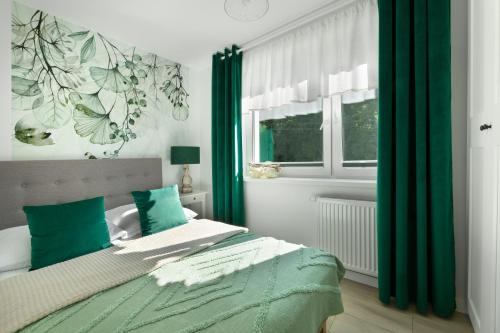 a bedroom with a bed with green curtains at "APARTAMENT STARY ZDRÓJ 3B" w centrum z balkonem, ogrodem i parkingiem in Kudowa-Zdrój